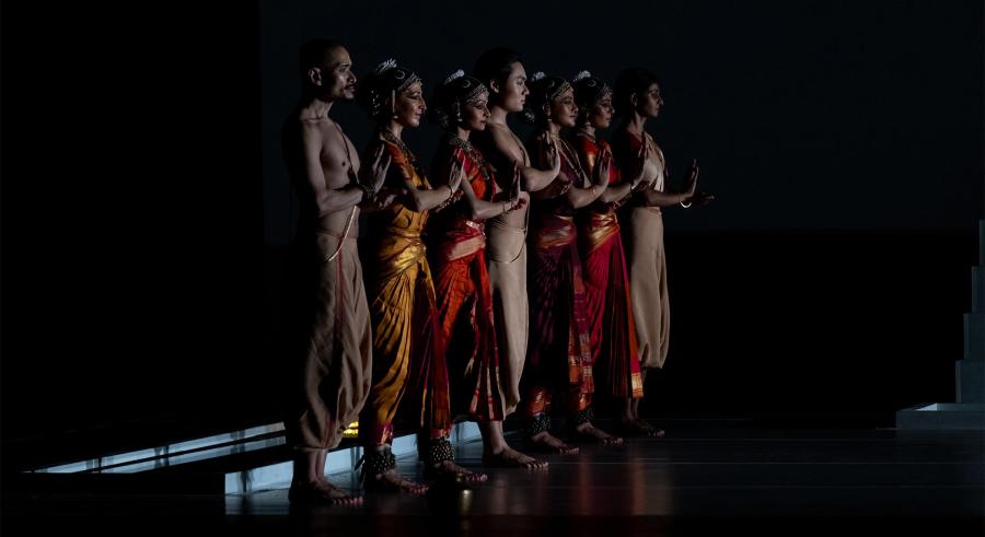 Dancers in different costumes in a line.