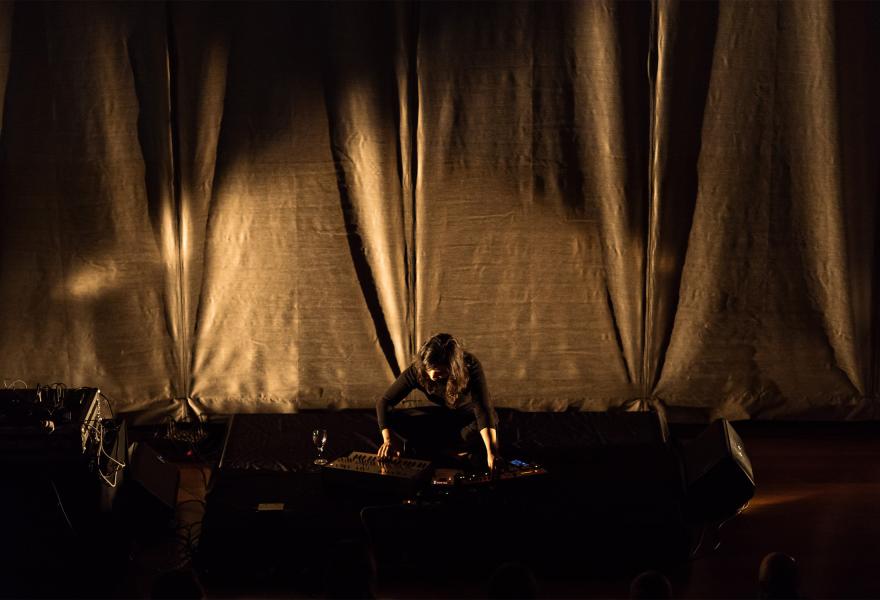 Overhead view of Sarah on stage with electronic music equipment, playing at a console