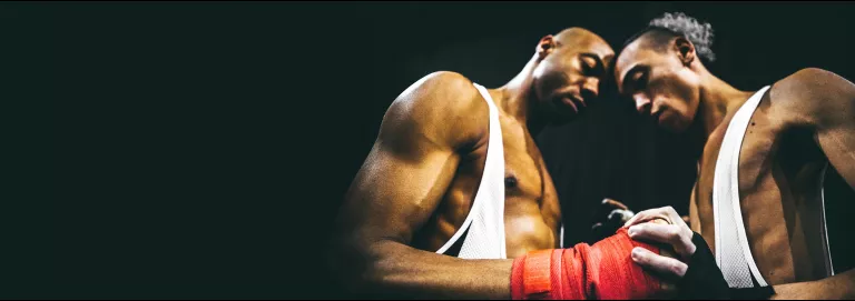 Two boxers join hands and press their heads together.