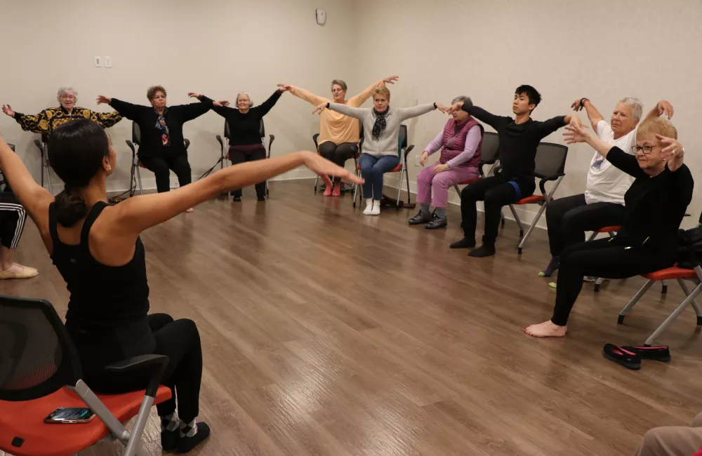 People sitting in a circle with their arms up.