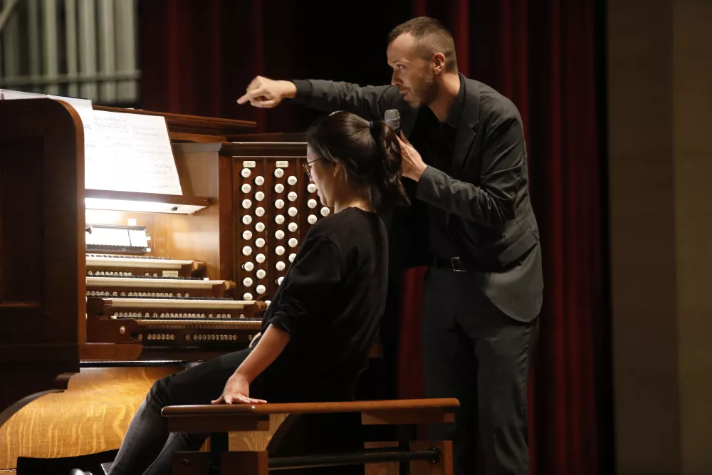 Organist instructing student sitting at organ.