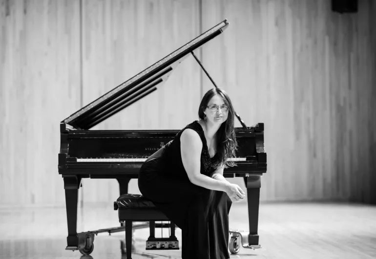 Ann DuHamel sitting next to a piano