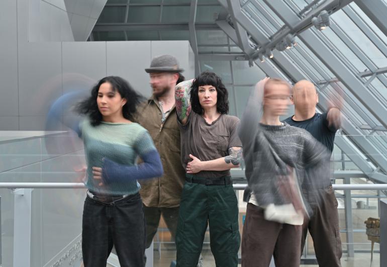Members of BRKFST in various poses. Four of five have blurred movement of head or arm; the fifth is stationary at center of the group.