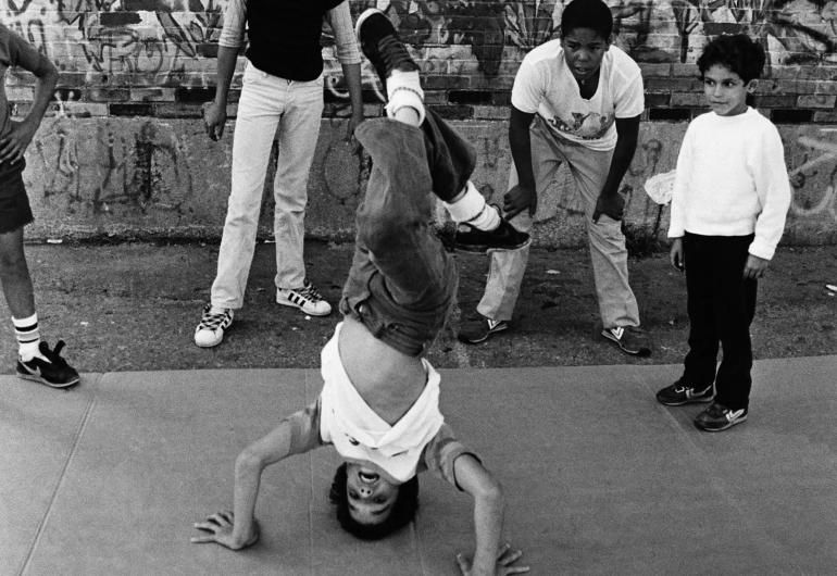 Black and white 1984 photo of children breakdancing in the street.