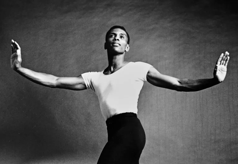 Arthur Mitchell. Image in black and white of Arthur Mitchell as a young man standing with his arms outstretched in a dance pose.