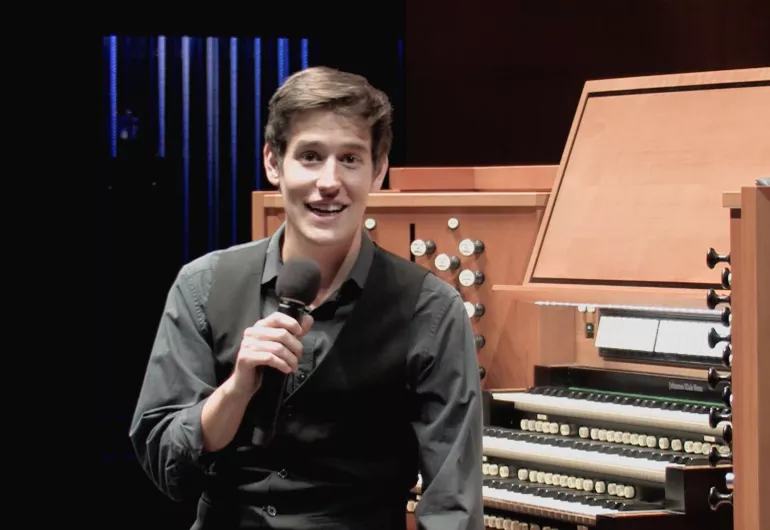 Greg Zelek sits at the organ with a microphone