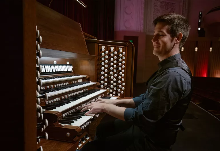 Greg Zelek smiles while playing the Northrop organ