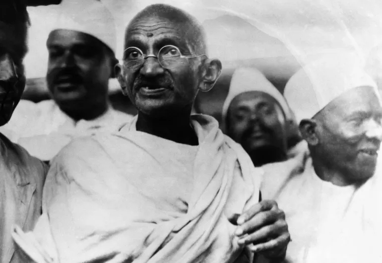 Black and white image of Gandhi wearing a white sari.