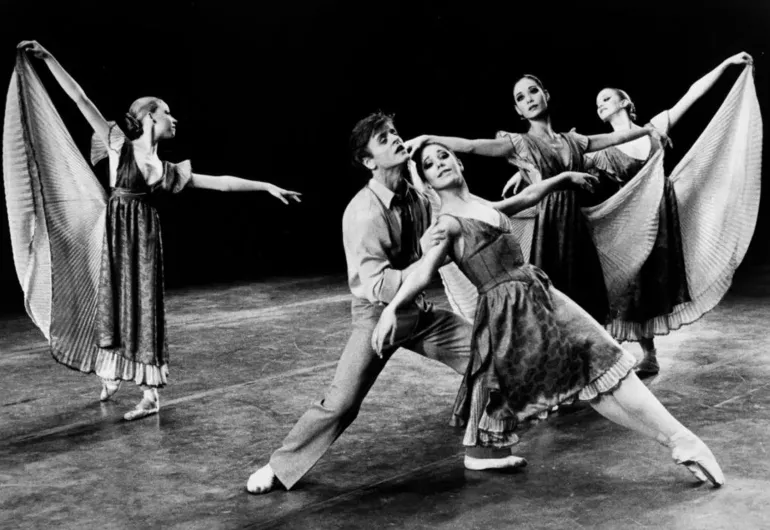 Five dancers wearing flowy costumes posed elegantly on stage.