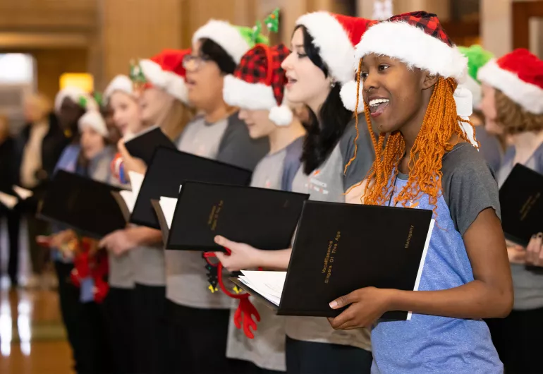 Teenagers sing wearing Santa hats.