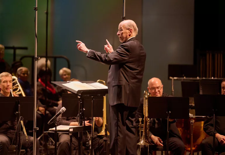 The conductor stands in front of the artists.