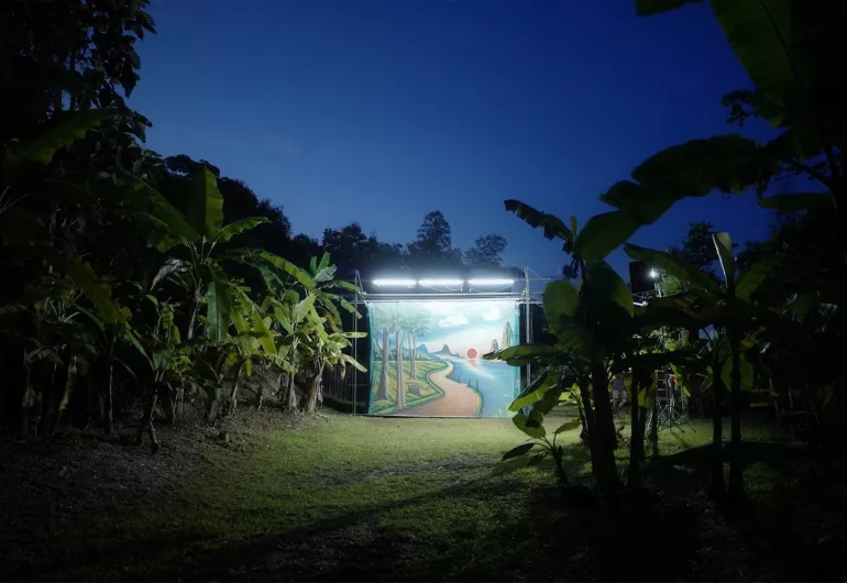 Freestanding screen with lights displaying an illustration of a path to blue water and a sunset.