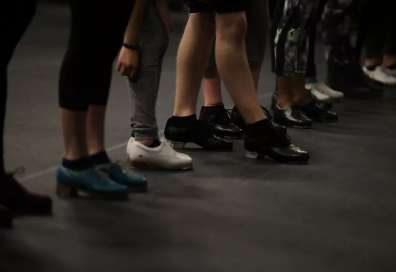 Line of tap dancers focused on their feet 