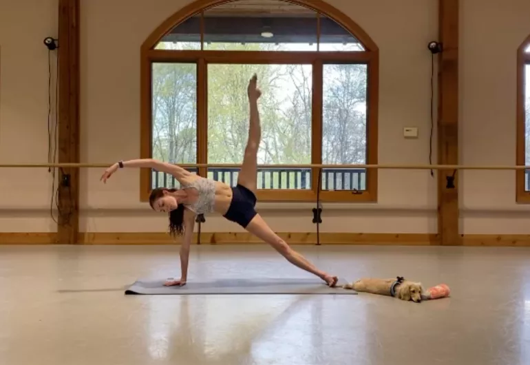 Kathryn Boren stretches on a mat while her dog lays close by.