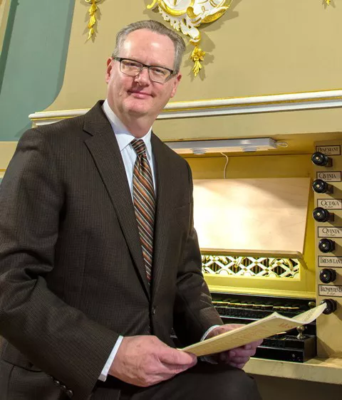 Dean in front of a light colored organ.