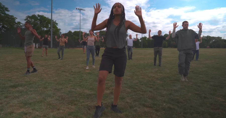 A group of people stand outside with their hands up.