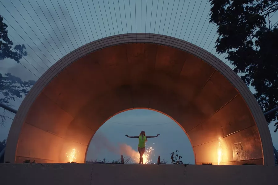 A person stands with their arms wide in a concrete tunnel