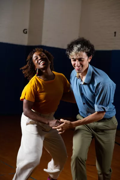 Two dancers perform together in a gymnasium setting.