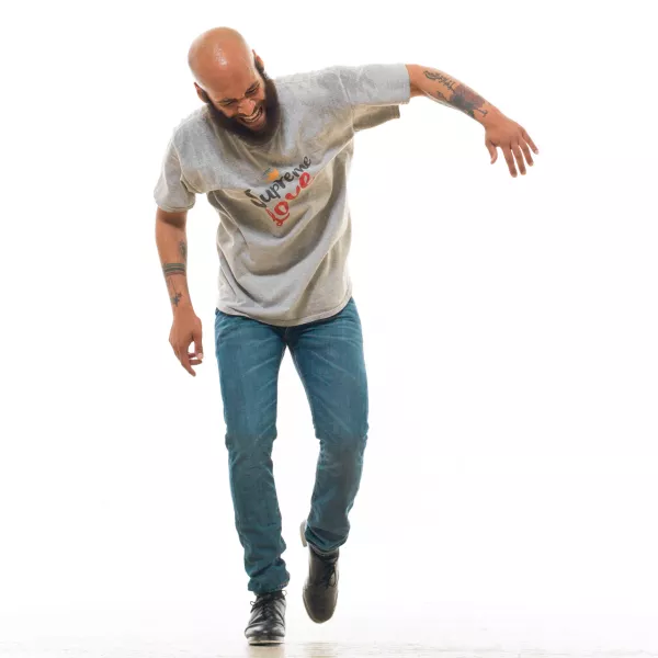 A dancer smiles while tapping against a white backdrop.