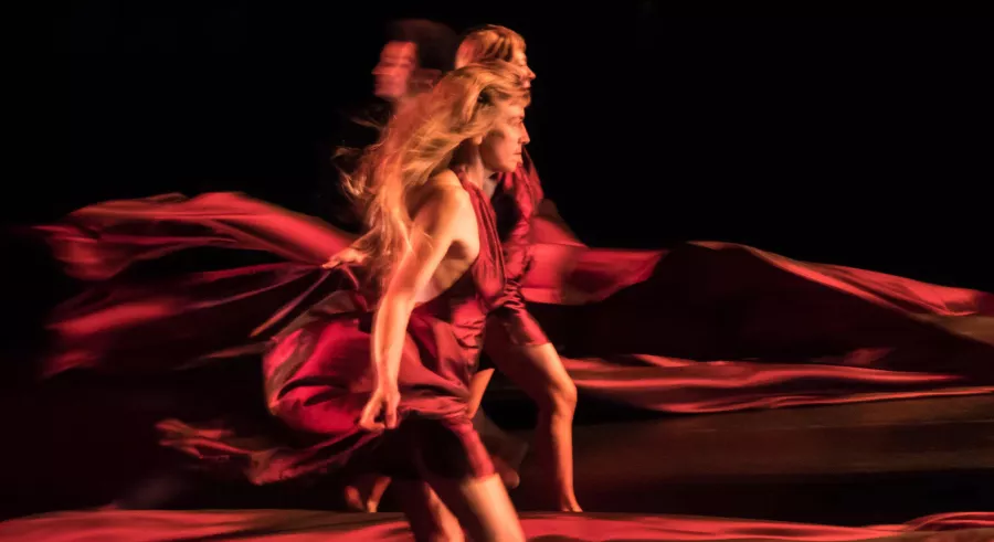 Dancers moving forward in red with flowing red fabric around them