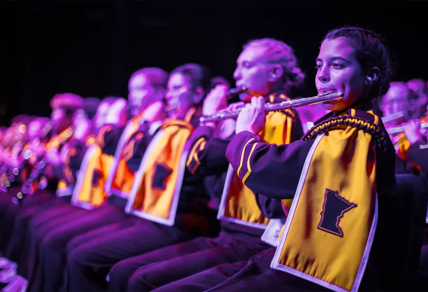 Line of flutists performing on a stage.