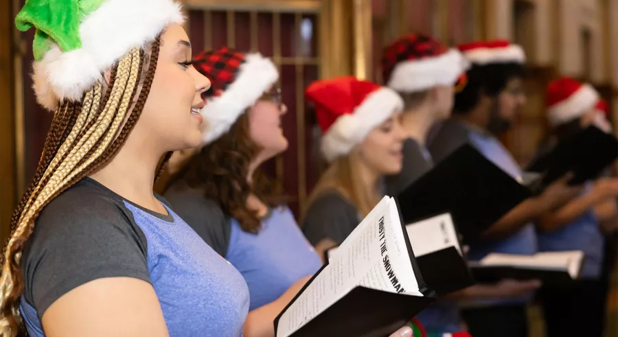 VocalEssence members perform carols wearing Santa hats.