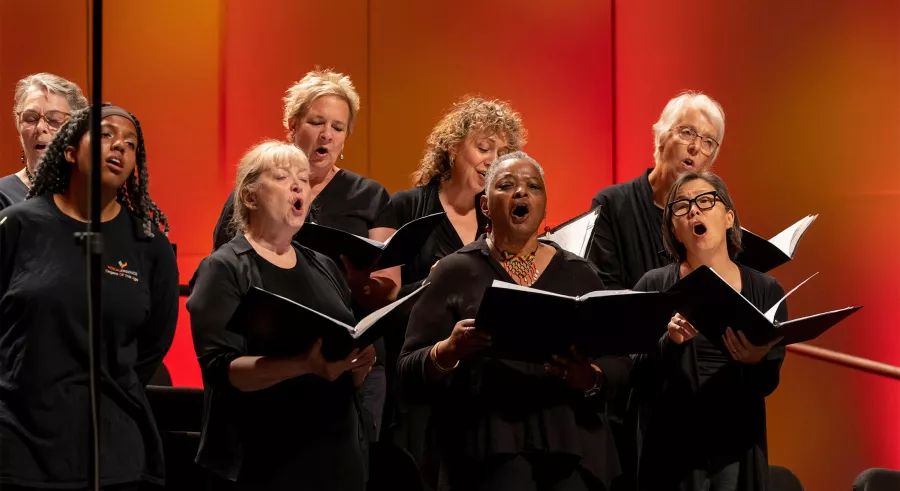 VocalEssence chorus sing holding open books.