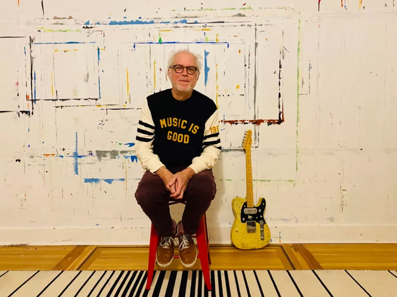 Bill Frisell sits in a red chair by a yellow guitar