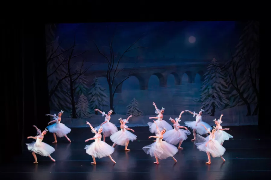 Ensemble of dancers in white costumes