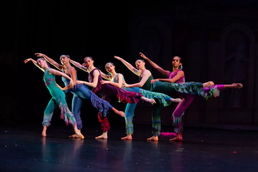 Dancers in arabesque wearing jewel tone costumes