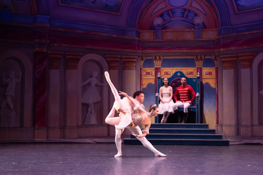 Two dancers in a lift pose dance in front of a pair sitting on a dias.