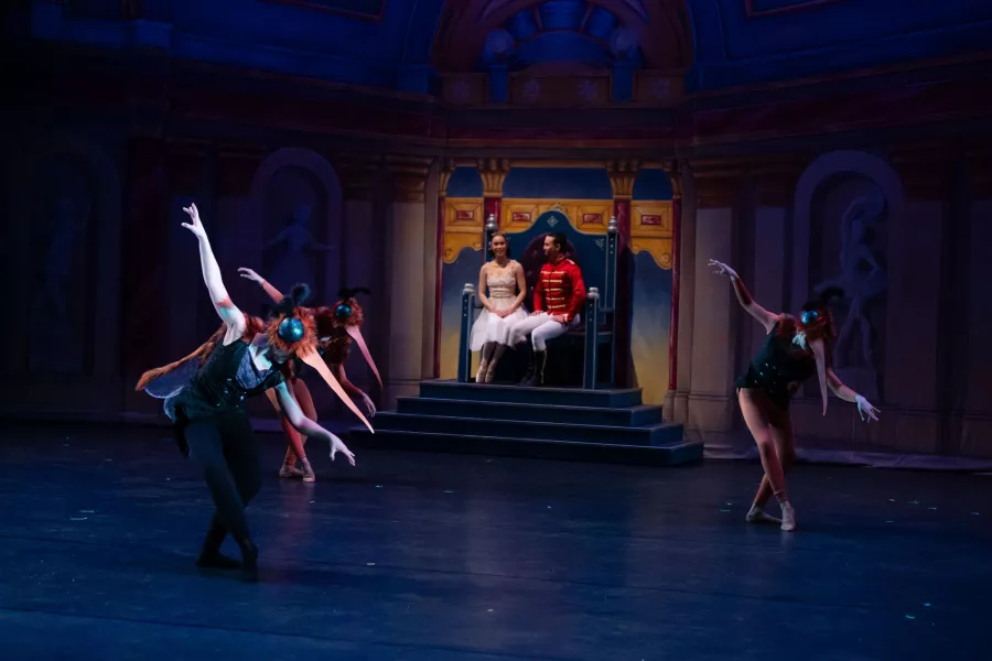 Group of dancers in mosquito costumes perform for the pair on the dias.