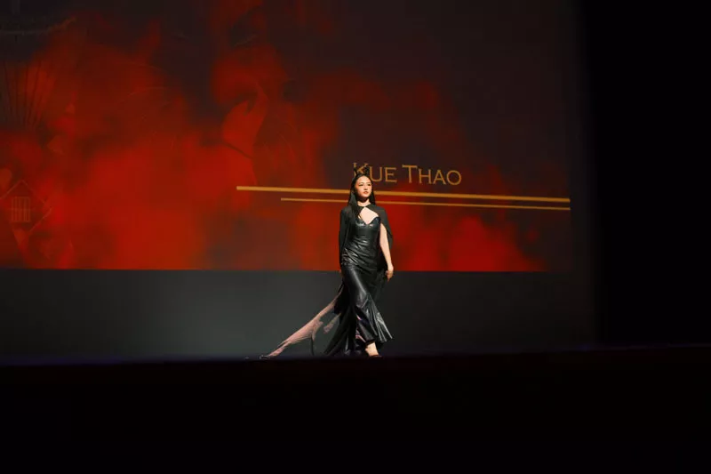 Woman walks the stage wearing a long black dress