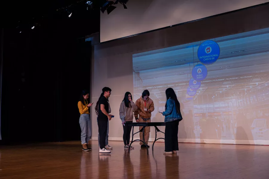 students at a table with video still of an airport